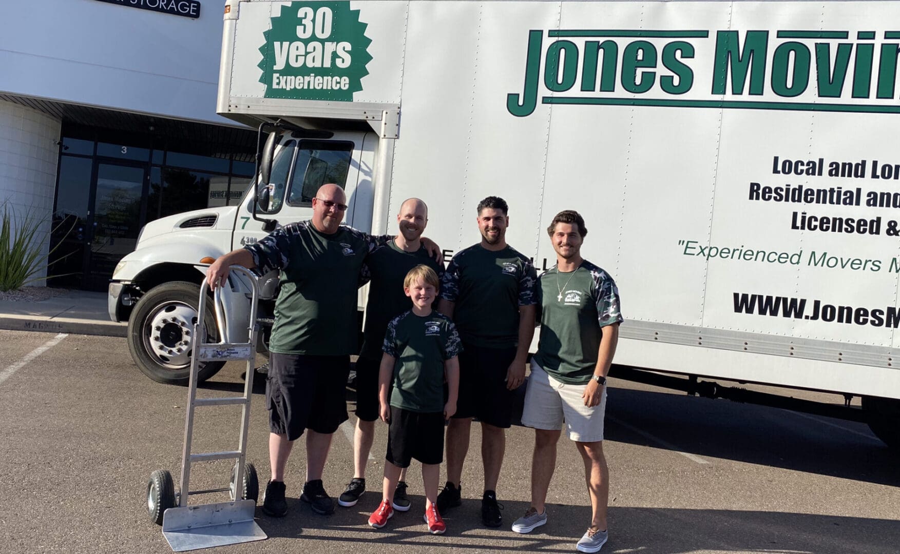 Five people standing beside a truck for a moving company
